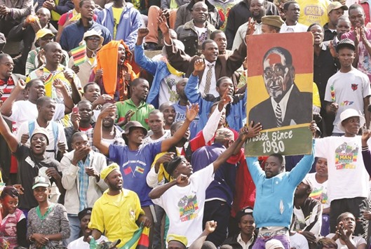 Robert Mugabeu2019s supporters holding a poster with his picture as he addressed mourners gathered for the burial of National Hero Charles Utete at the Heroes Acre in Harare yesterday.