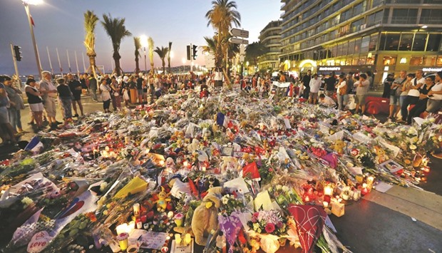 People stand in front of flowers, candles and messages laid at a makeshift memorial in Nice late on Monday, in tribute to the victims of the deadly attack on the Promenade des Anglais seafront which killed 84 people.