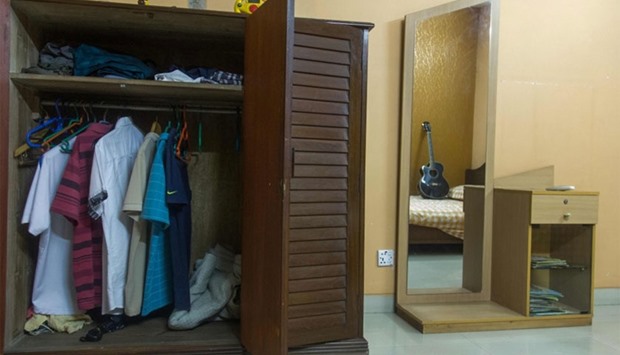 This photograph taken on July 4, 2016, shows a guitar standing on a bed and clothing hanging in a wardrobe of Mir Saameh Mubasheer at his family home in Dhaka