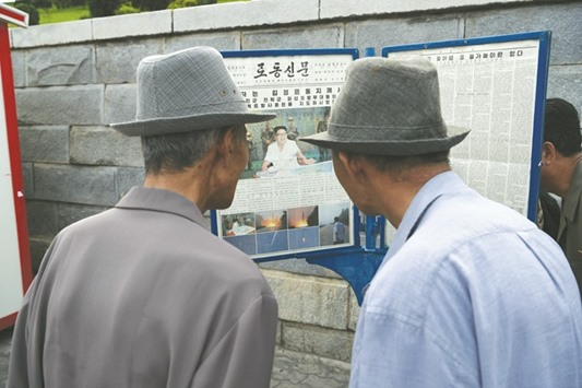 Two men read a copy of the Rodong Sinmun newspaper showing coverage of North Korean leader Kim Jong-Un overseeing a ballistic missile test conducted by the Hwasong artillery units of the KPA Strategic Force, in a public square in Pyongyang yesterday.