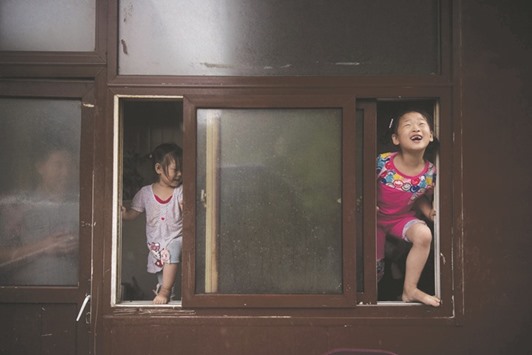PROOF OF LIFE: Two girls standing by a window are seen enjoying the rain in Beijing yesterday.