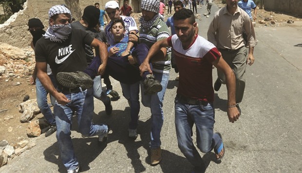 Palestinian protesters carry an injured teenager during clashes with Israeli security forces following a weekly demonstration against the expropriation of Palestinian land by Israel in the village of Kafr Qaddum, near Nablus in the occupied West Bank yesterday.