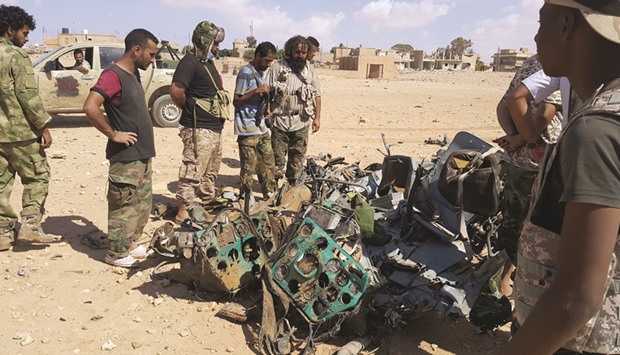 Libyans gather around the remains of a helicopter that crashed near Benghazi yesterday.
