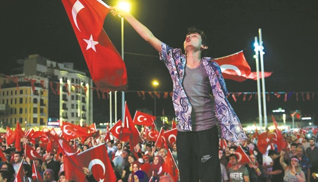 SUPPORT ANYTHING BUT FLAGGING: A young man waves the Turkish flag as others gathered for a meeting in support of the Turkish president on Istanbulu2019s Taksim Square late on Tuesday.