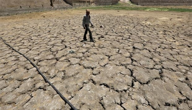 A man walks through a dried-up Sarkhej lake on a hot summer day in Ahmedabad, India.