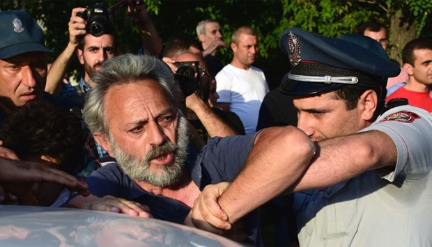 Armenian police detain an opposition supporter, artist Niko Aghangegyan, next to a police check point blocking the streets to Erebuni police station in Yerevan on July 17, 2016.