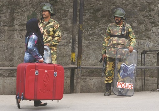 A paramilitary trooper stands guard as a woman walks past on the 14th day of a curfew in downtown Srinagar yesterday.