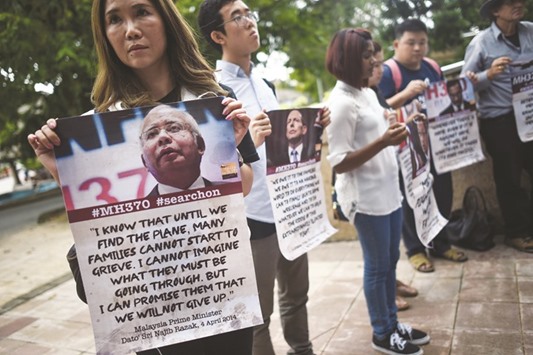 Relatives of passengers missing on Malaysia Airlines Flight MM370 hold placards after a joint press conference of the Ministerial Tripartite Meeting on the search for the missing flight at the Malaysian federal administrative centre in Putrajaya, outside Kuala Lumpur.