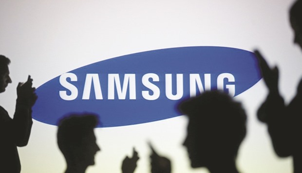 People are silhouetted as they pose with mobile devices in front of a screen projected with a Samsung logo in Seoul. The South Korean firm sued Huawei in a Beijing court for allegedly infringing six of its patents, a spokeswoman said yesterday.