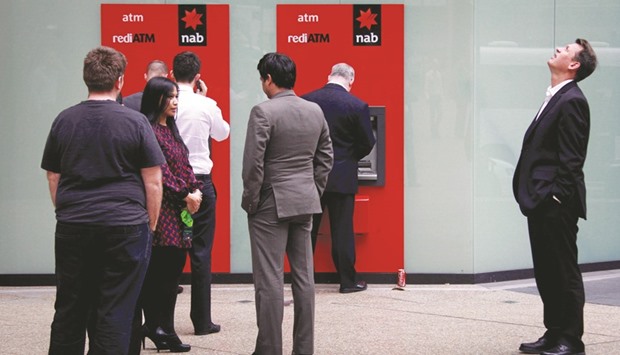 A man looks up as he stands next to a line for two National Australia Bank automatic teller machines in Sydney. After exiting struggling UK operations and selling a controlling stake in its life insurance business, NAB CEO Andrew Thorburn is under pressure to boost growth at home where the bank has underperformed its three big rivals in recent years.