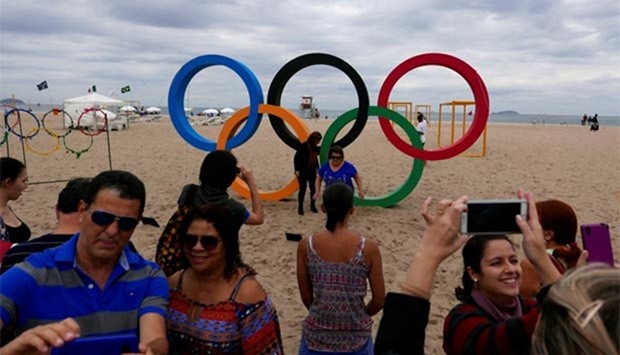 People pose for pictures in front of the Olympic Rings, at the Copacabana beach ahead of the 2016 Rio Olympic Games.