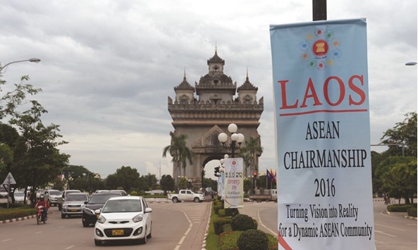 Commuters ride past the victory tower Patuxay and a banner for the 49th annual ministerial meeting of the Association of South East Asian Nations (Asean) in Vientiane.