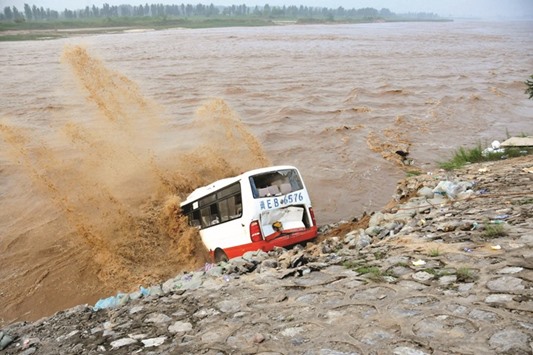 An abandoned bus filled with sand bags is used to build a makeshift dike at a flooded area in Xingtai, Hebei province.
