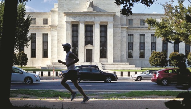 A runner passes the Federal Reserve building in Washington, DC. The Fed is all but certain to keep interest rates on hold on Wednesday, acknowledging improved economic prospects but offering few hints about its next move, keen to avoid repeating its past mistake of stoking rate hike expectations.