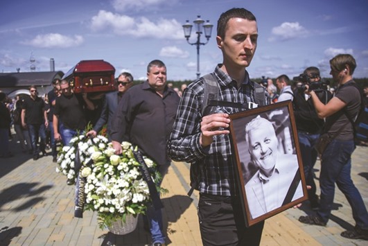 People carry the coffin and a portrait of Belarus-born journalist Pavel Sheremet, who was killed in a car bomb in central Kiev three days ago, during a funeral ceremony at the Church of All Saints in Minsk.