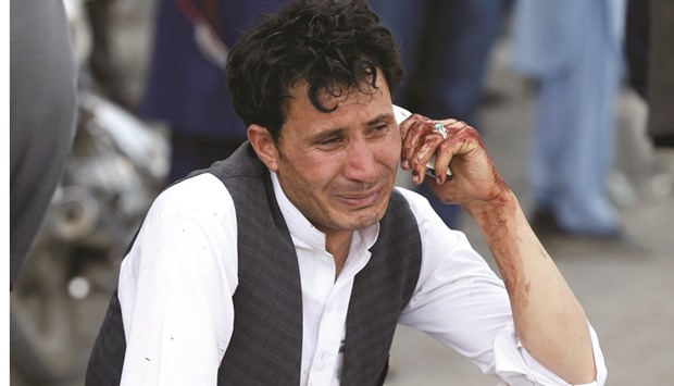An Afghan man talking on his phone after the suicide attack in Kabul yesterday.