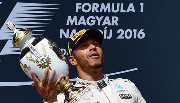 Lewis Hamilton celebrates his victory with the trophy on the podium at the Hungaroring circuit in Budapest on Sunday.