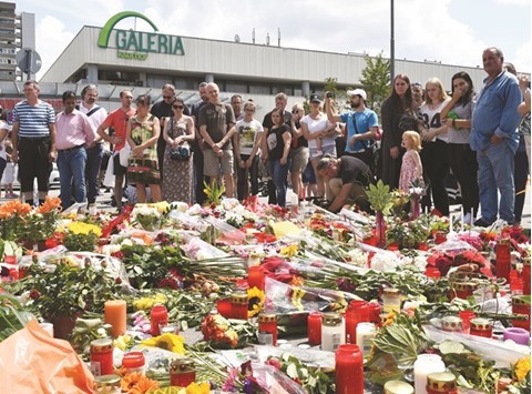 People mourn at a memorial of candles and flowers in front of the Olympia Einkaufszentrum shopping centre in Munich yesterday.