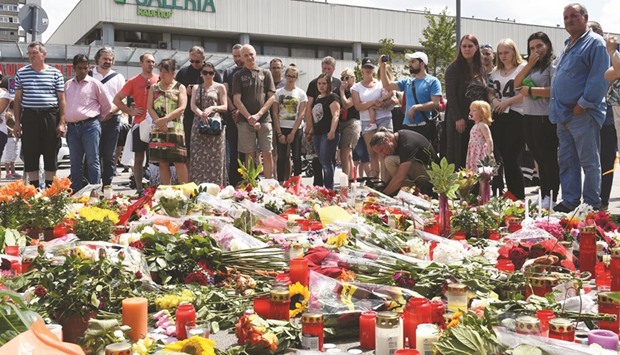 People mourn at a memorial of candles and flowers in front of the Olympia Einkaufszentrum shopping centre in Munich yesterday.