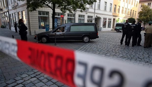 Police watch a hearse leave the scene of a suicide attack in the southern German city of Ansbach on Monday.
