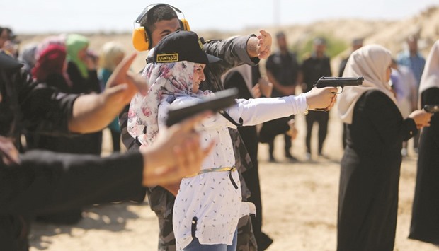 A Palestinian girl aims a pistol as she prepares to fire at a target during a training session for the families of Hamas officials, organised by Hamas-run Security and Protection Service, in Khan Younis in the southern Gaza Strip yesterday.