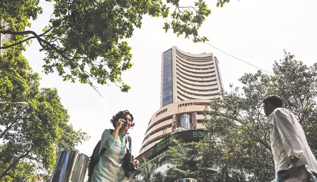 Pedestrians walk past the Bombay Stock Exchange building in Mumbai. The Sensex closed up 292.10 points to 28,095.34 yesterday, after changing direction 10 times in the first hour of trade.