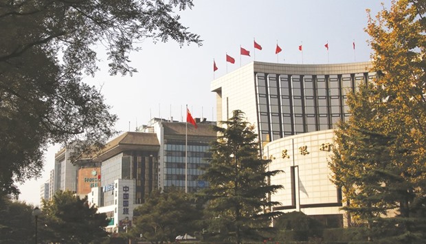 The Peopleu2019s Bank of China headquarters (right) is seen in Beijing. The PBoC kept the yuan from slipping past 6.7 per dollar last week by strengthening its reference rate, which limits onshore moves to 2% on either side, even as the greenback advanced.