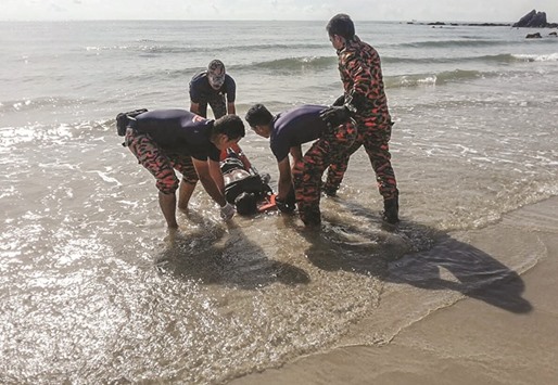This undated handout photo released by the Malaysia Fire and Rescue Department yesterday shows officers transporting a victim found at sea after a boat, carrying 62 Indonesians thought to be illegal immigrants, capsized due to strong waves at Batu Layar Beach, southern state of Johor.