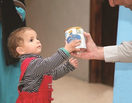 Qatar Charity personnel distributing formula milk to children in Aleppo.