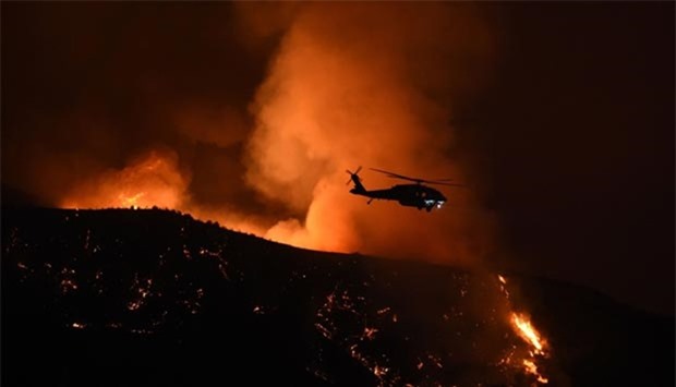 A firefighting helicopter makes a drop at Fair Oaks Canyon during the Sand Fire in Santa Clarita, California on Sunday.
