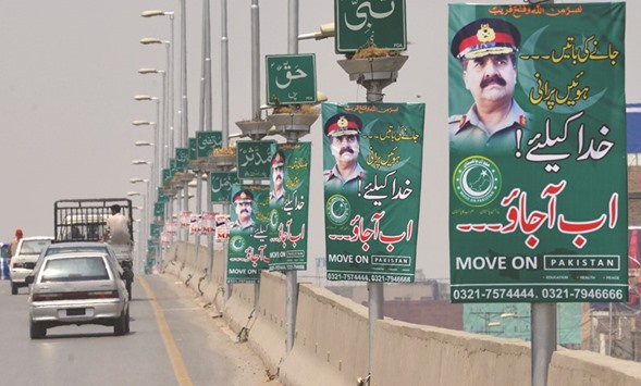 Pakistani commuters drive past posters of army chief General Raheel Sharif in Peshawar on July 12, 2016. Posters begging Pakistanu2019s powerful army chief to launch a coup appeared in major cities including the capital Islamabad overnight July 12, raising eyebrows in a country that has been ruled by the military for more than half its history.