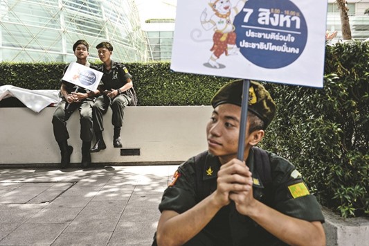 Students doing military service take a break yesterday during a campaign in Bangkok encouraging the public to vote in the upcoming referendum on Thailandu2019s draft constitution.