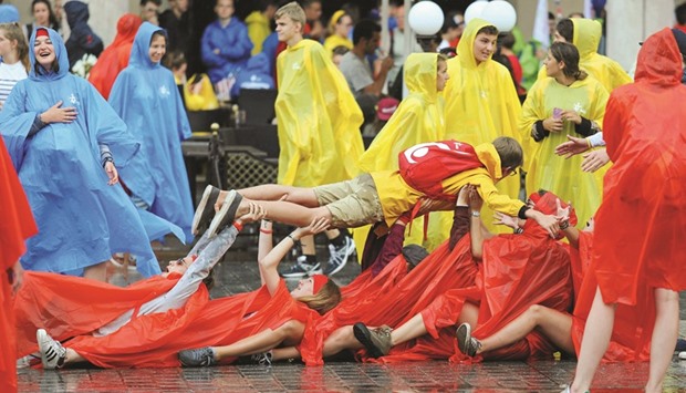 Pilgrims in rain coats play during heavy rain on World Youth Day at the main square in Krakow.
