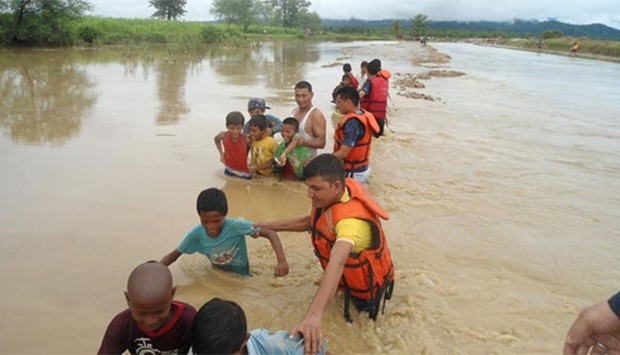 Nepalese police personnel guide children through floodwaters at Babai muinicipality in Bardiya, some 400 kms southwest of Kathmandu.