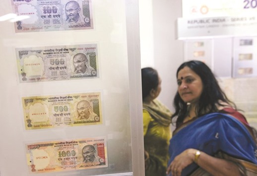 People walk past currency notes displayed in an exhibition of the Reserve Bank of India  in Mumbai (file). The rupee is Asiau2019s worst performer after the yuan since Chinau2019s shock devaluation of its currency roiled global markets and spurred a flight from Indian stocks and bonds.