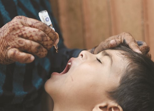 A Pakistani health worker administers polio vaccine drops to a child during a door-to-door polio campaign in Karachi on July 25.