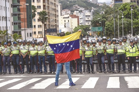 A member of the Venezuelau2019s opposition gestures showing a national flag in front of National policemen during a demonstration in Caracas.