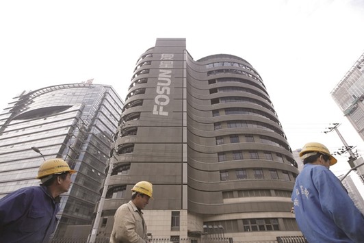 Construction workers walk past the headquarters of Fosun International in Shanghai. The firm is looking for opportunities in Britain and Europe, in markets rendered increasingly volatile by Britonsu2019 vote to leave the European Union, a top official said.