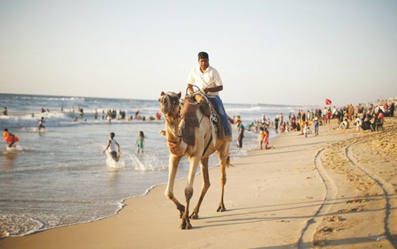 A Palestinian man rides a camel on a beach in Gaza City.