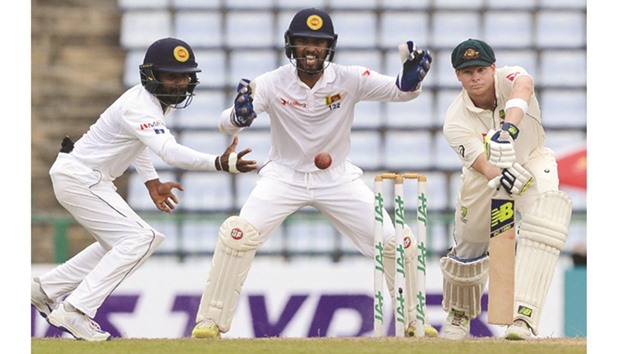 Sri Lankau2019s Kaushal Silva (left) attempts to field a ball hit by Australiau2019s captain Steven Smith (right) as wicketkeeper Dinesh Chandimal looks on during the fourth dayu2019s play in the opening Test in Pallekele yesterday.