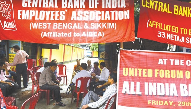 Indian bank employees sit next to the closed gates of a bank in Kolkata. Banking operations across India were hit as around hundreds of thousands of employees of private and nationalised banks stopped work for a day to protest against central governmentu2019s policies for the sector.