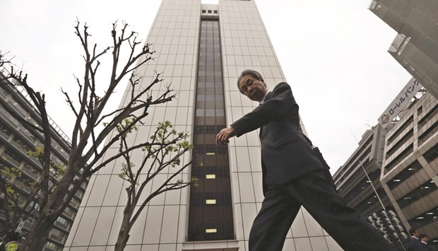 A pedestrian walks past the building housing the Government Pension Investment Fund headquarters in Tokyo. The worldu2019s biggest pension fund posted the worst annual performance since the global financial crisis, with losses exacerbated by unfavourable currency moves and a foray into equity markets