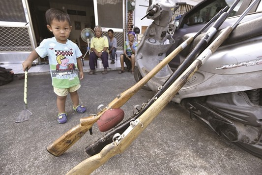 Tama Talumu2019s son stands next to shotguns in front of his home in Taitung.