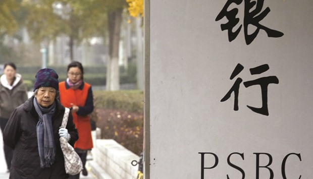 People walk past a signboard of Postal Savings Bank of China in Beijing. The bank raised 45bn yuan ($6.8bn) in December selling about a 17% stake to investors including Canada Pension Plan Investment Board, JPMorgan Chase & Co and UBS Group.