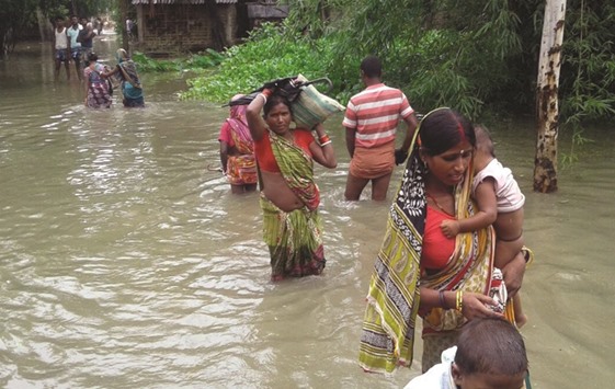 Villagers negotiate their way in a flooded village in Katihar district of Bihar.