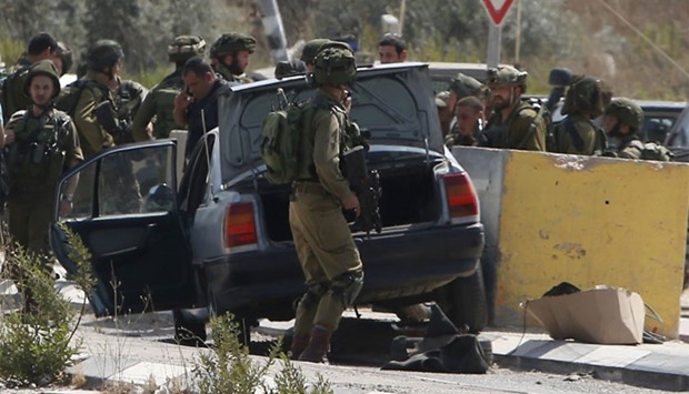 Israeli soldiers gather next to a vehicle belonging to a Palestinian man after he reportedly charged it into a group of soldiers at the Israeli army Hawara checkpoint near the city of Nablus in the occupied West Bank.