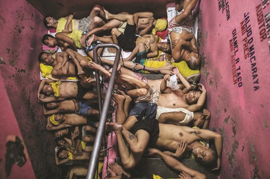 Inmates sleep on the steps of a ladder inside the Quezon City jail at night in Manila.