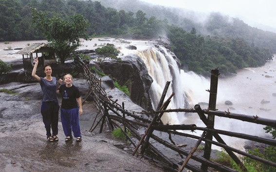 Tourists pose at a waterfall in Kerala during a monsoon tour last month.
