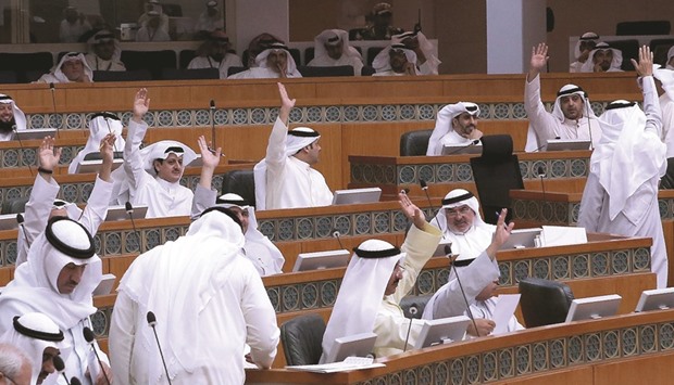 Kuwaiti MPs raise their hands as they vote during a parliament session at the Kuwaitu2019s National Assembly in Kuwait City yesterday. Kuwait said it plans to tap the international debt market through bond issues to finance its budget deficit after recording a first shortfall in 16 years.