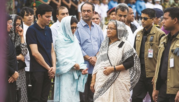 Bangladesh Prime Minister Sheikh Hasina, third right, walking past family members of a policeman during a memorial service for those killed in a bloody attack and seige in Dhaka, yesterday.
